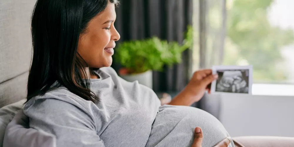 Pregnant woman looking at a print out of her scan