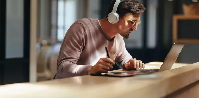 A person wearing headphones and lookin intently at a laptop